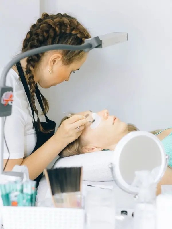 A lash artist applying extensions under the lamp