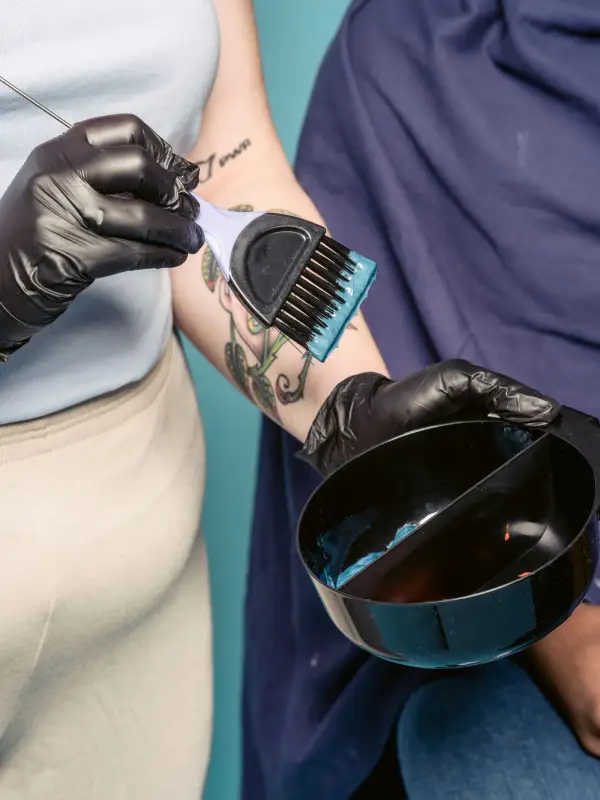 A hairdresser applying colour to a client's hair with a brush