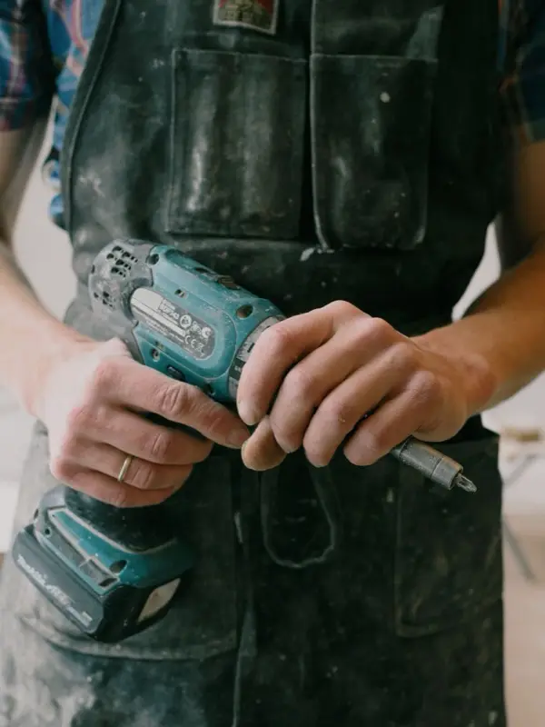 A master in a work apron with a cordless screwdriver on a call-out