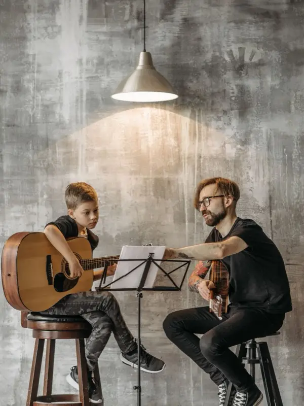 A guitar teacher working with a student in a music studio