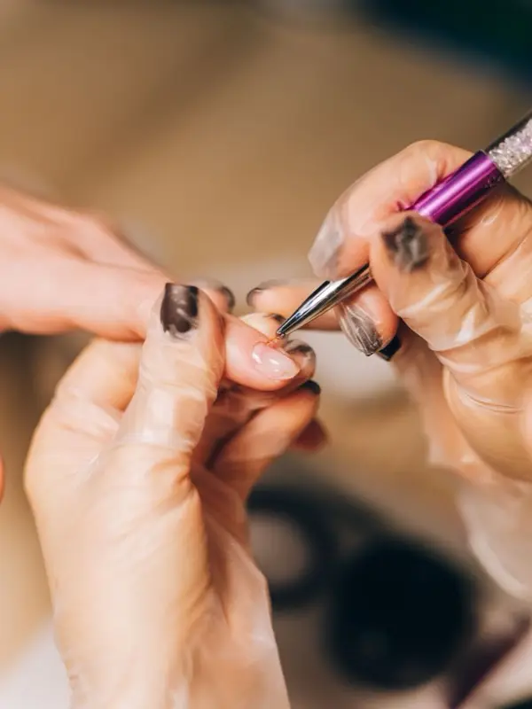A nail technician applying gel polish for a client