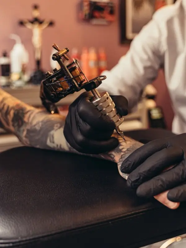 A tattoo artist working on a client's tattoo with the machine