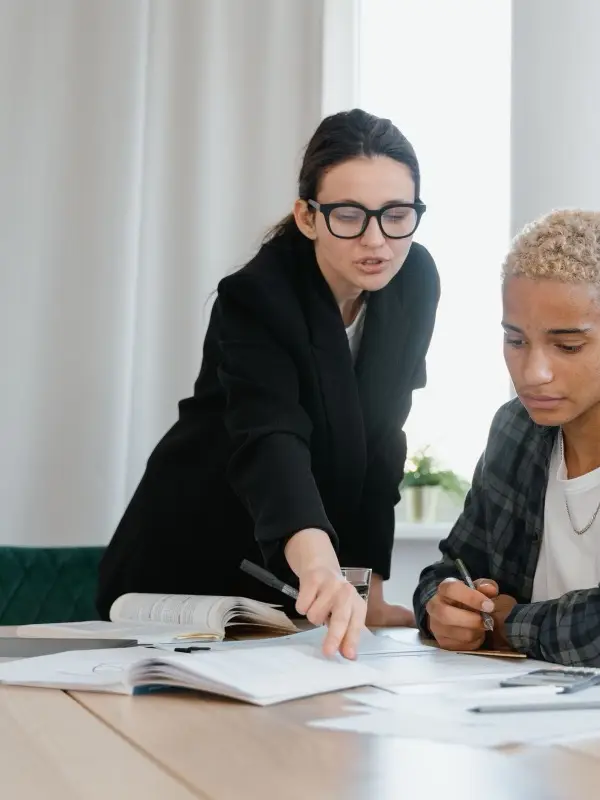 A tutor working through an exercise with a student at the desk