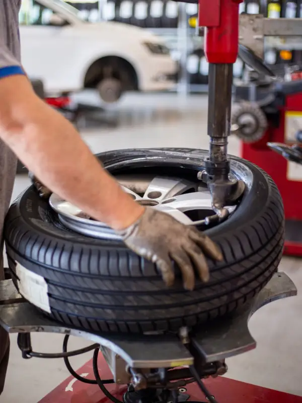 A tyre fitter's gloved hand holding a wheel on a tyre changer